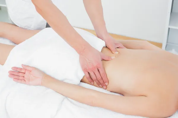 Mid section of a physiotherapist massaging woman\'s back