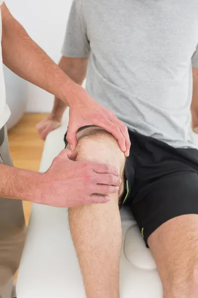 Close-up mid section of a man getting his knee examined