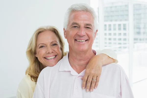 Happy senior woman embracing man from behind