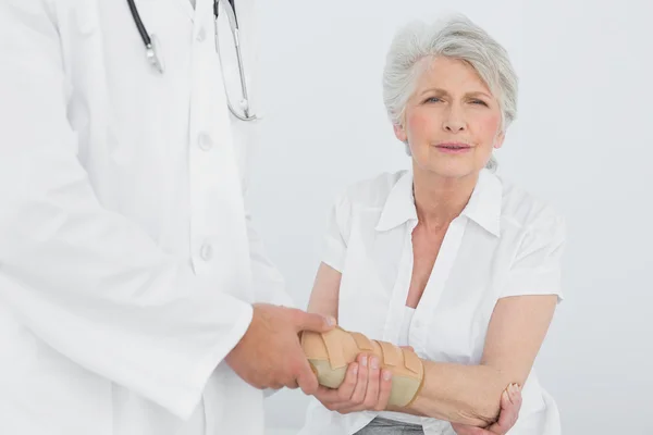 Male physiotherapist examining a senior woman\'s wrist