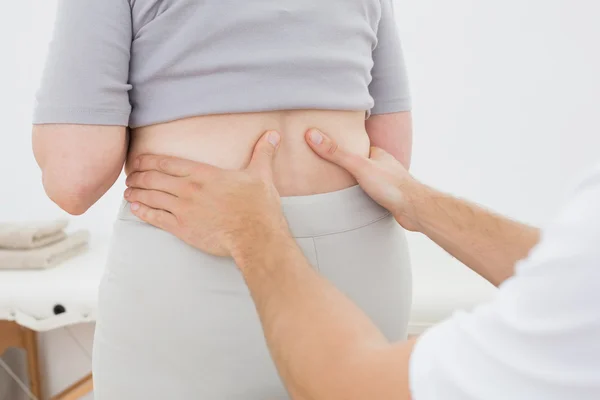 Mid section of a physiotherapist examining woman's back