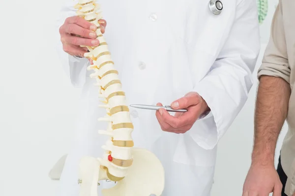 Mid section of a doctor explaining the spine to a patient