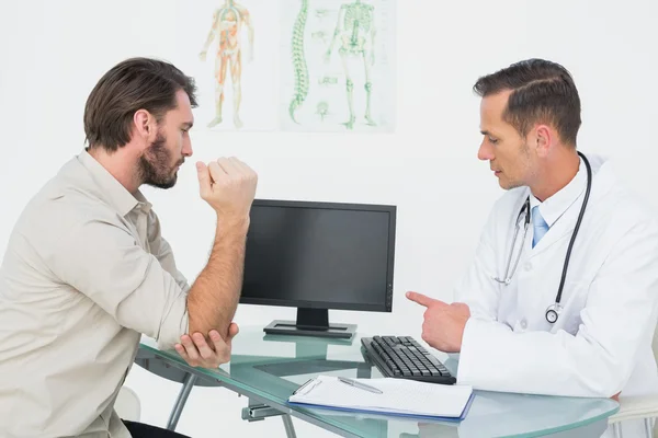 Male doctor in conversation with patient at desk