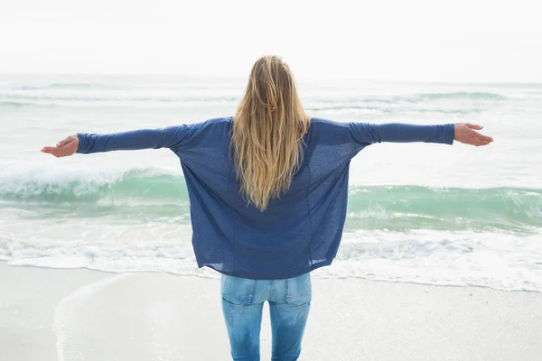 Rear view of a blond with arms outstretched at beach