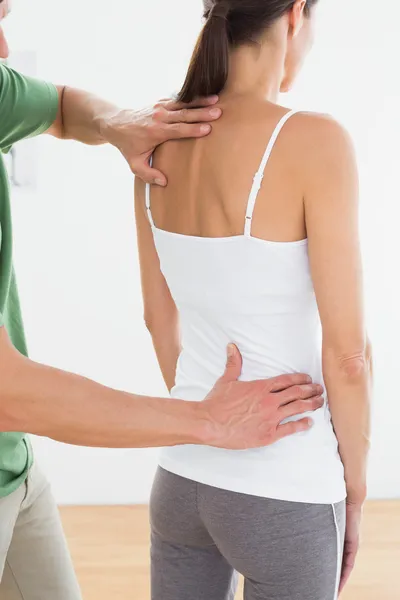 Physiotherapist examining woman's back in medical office