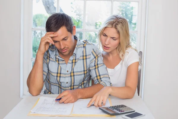 Worried couple with financial documents and calculator