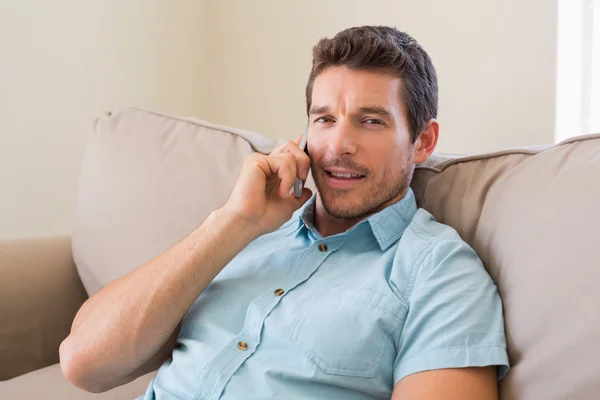 Smiling man using mobile phone in living room