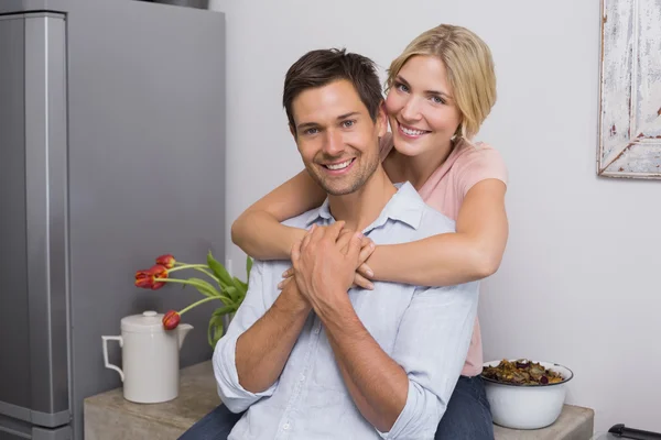 Smiling woman embracing man from behind at home