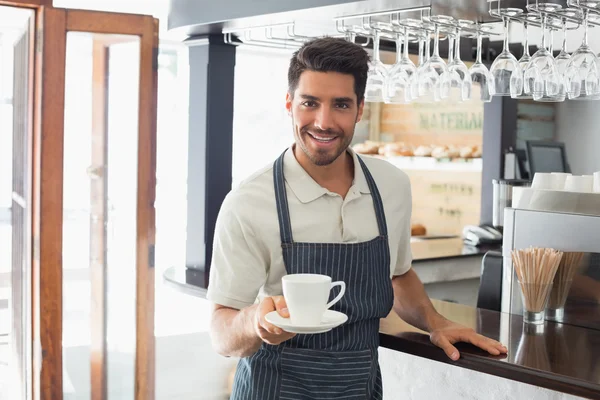 Waiter holding cup of coffee at cafe