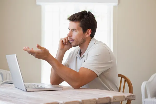 Young man using mobile phone and laptop