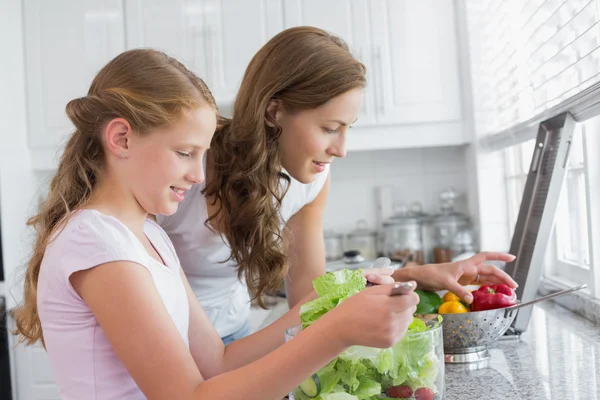 Girl helping mother to cut vegetables in kitchen