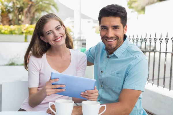 Smiling couple using digital tablet at cafe
