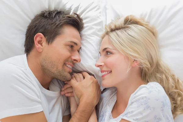 Loving couple looking at each other while lying in bed