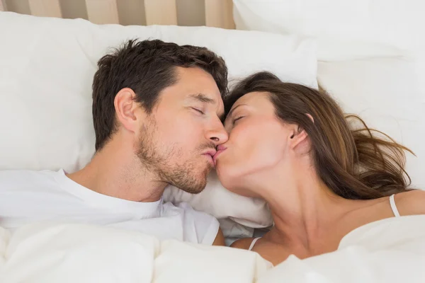 Relaxed couple kissing in bed