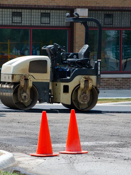 Road construction machine and caution cones on job site