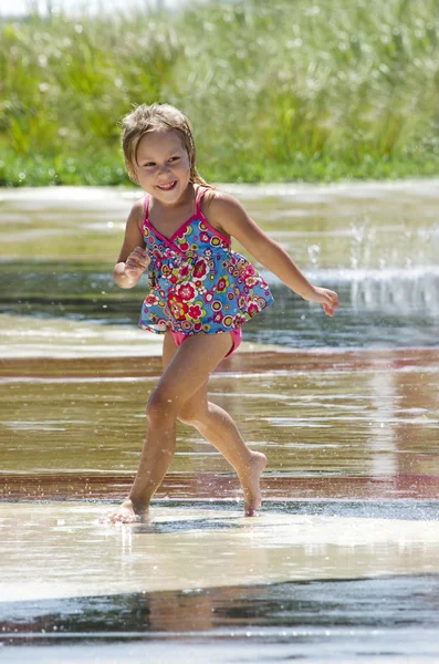 在一个夏天的喷泉中跳舞的快乐女孩 - 图库照片