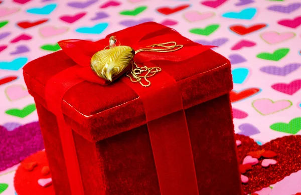 Red gift box with heart necklace on a heart back ground