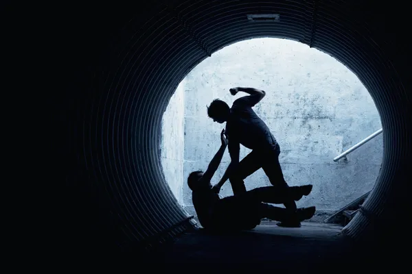 Young man being mugged in a dark tunnel