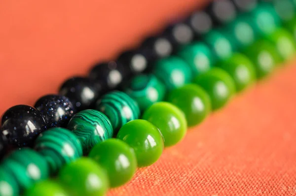 Green and black beads from a stone on a coral background