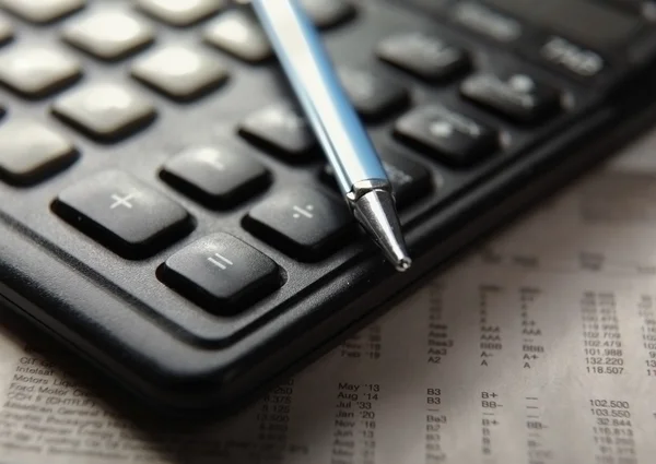 Close-up of pen and calculator on paper table numbers.