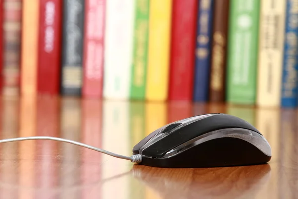 A computer mouse against books