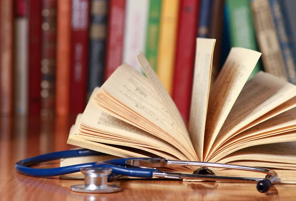 A stethoscope is lying with a book on the desk