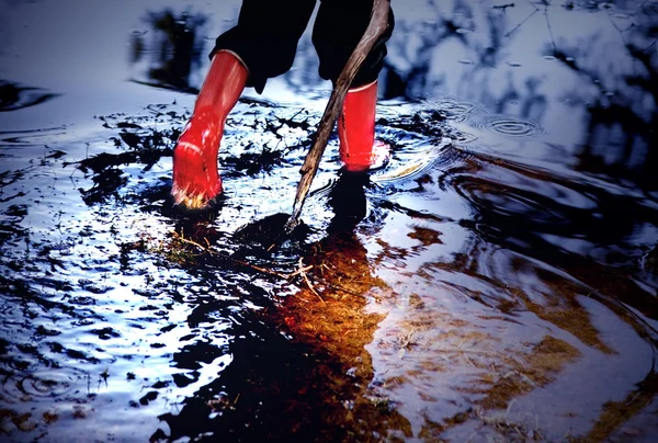 Child With Rubber Boots Walking In Puddle