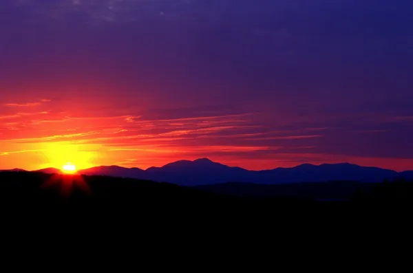 The Sun And Colored Sky Over Mountain Range