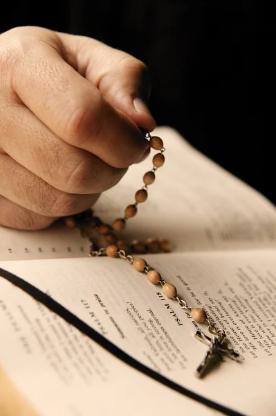 A Hand Holds A Rosary And Bible