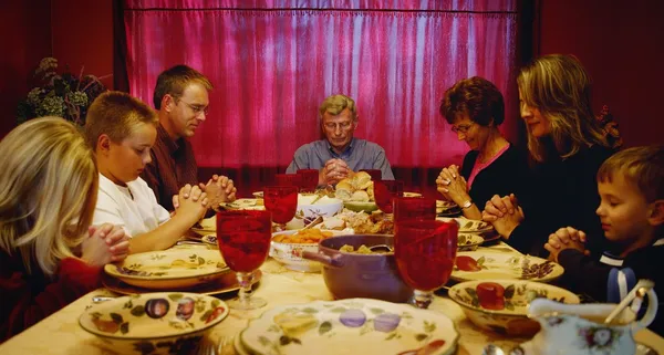 Family Praying Around Thanksgiving Table