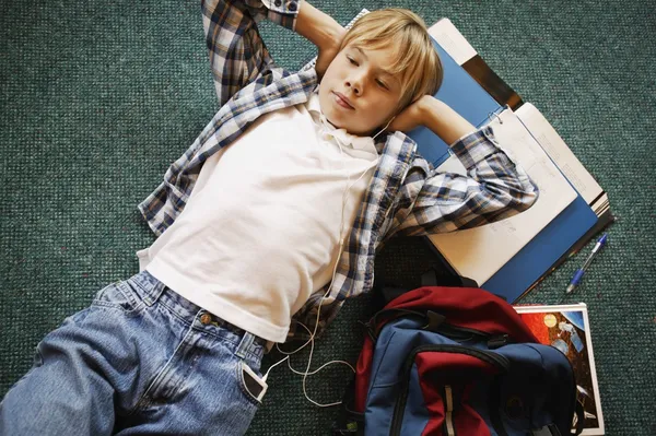 Boy Laying On Floor Listening To Music While Doing Homework