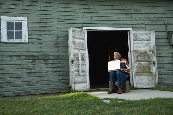 Man Working On Computer Outside Of Barn Or Shed