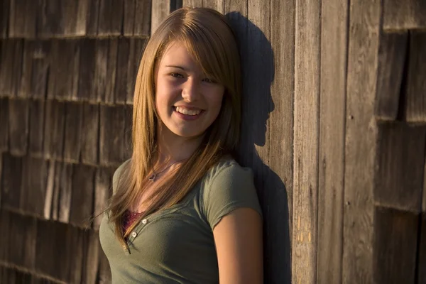 Young Woman Stands Against Old Wooden Building