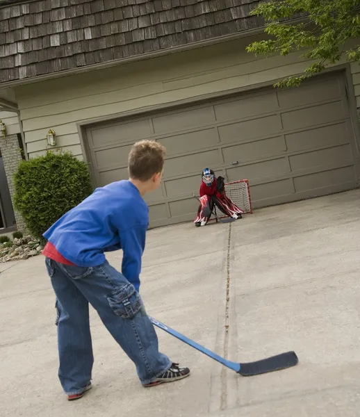 Boys Playing Hockey On Driveway