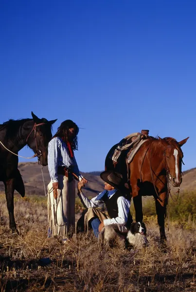 Cowboy And Cowgirl Holding Hands Beside Their Resting Horses, Ponderosa Ranch.