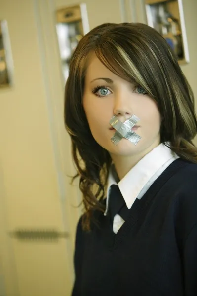 Female Student In Uniform With X Taped Over Mouth