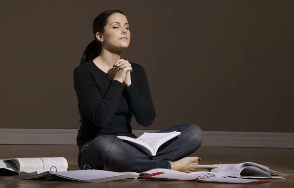Woman Praying While Studying On Floor