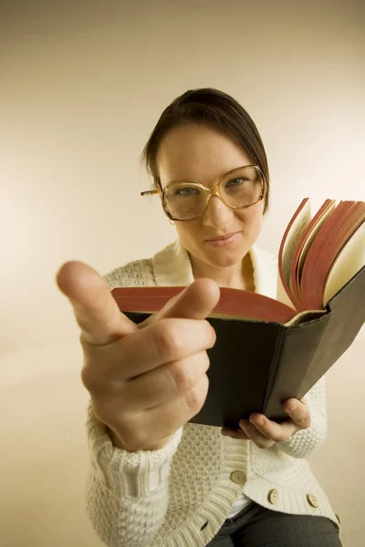 A Woman Holding Book And Pointing To The Camera