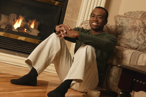 A man is sitting in a room near the fireplace