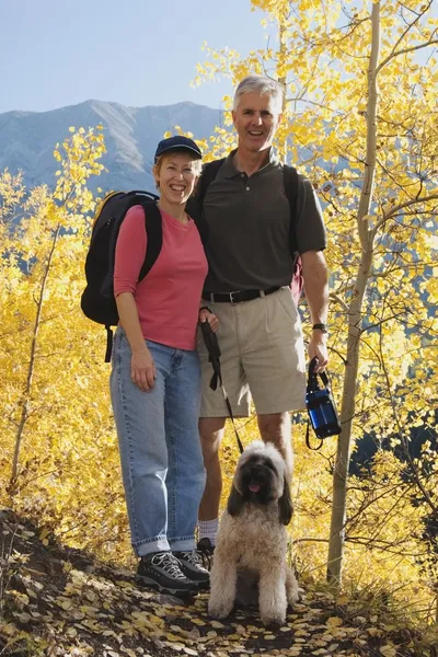 Couple Hiking With A Dog In A Mountains In The Autumn
