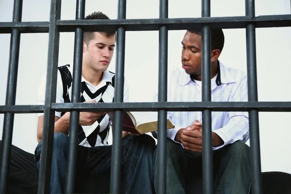 Young Man Reads The Bible To Another Young Man In Jail