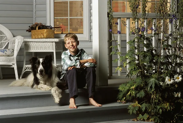 Boy Sitting With Dog On Porch Steps