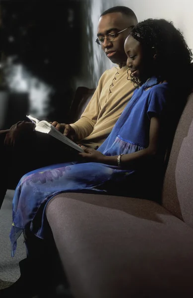 Man And Girl Reading Book On Couch