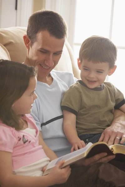 Father Reading The Bible To His Young Son And Daughter