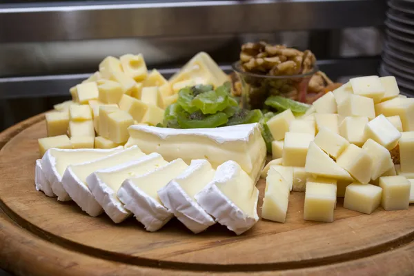 Assorted cheese and dried fruits on a wooden board