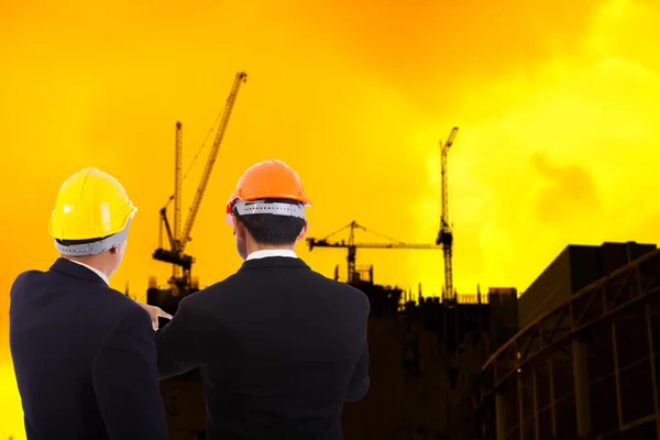 Construction engineers in helmets on background of building