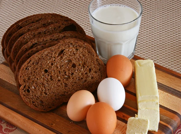 Bread, Butter, Eggs, Milk on a Cutting Board