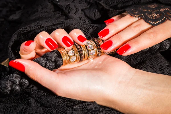 Female hands with red manicure on a black lace
