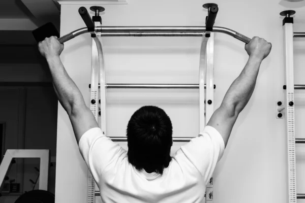 Man hanging from a pull up bar