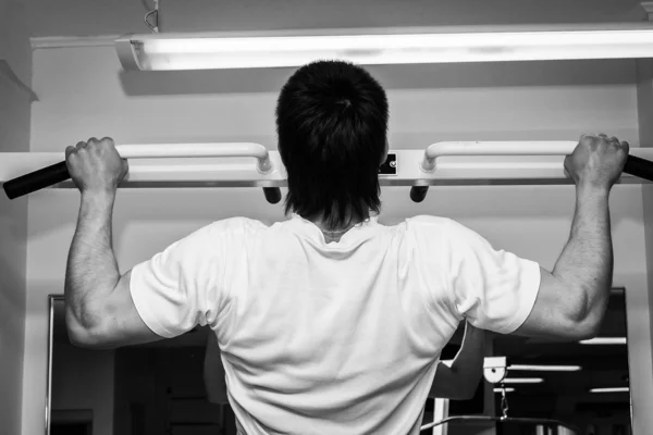 Man hanging from a pull up bar.